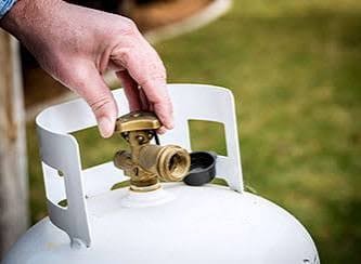Hand opening the valve on a residential propane cylinder